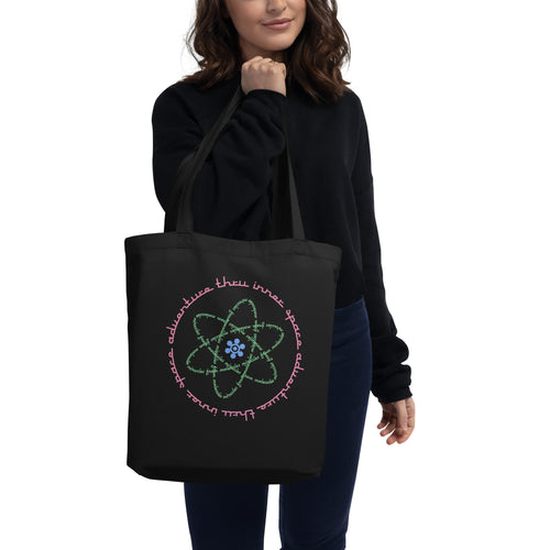 Logo inspired by the attraction with pink stylized retro text reading Adventures Thru Inner Space in a circle, surrounding atomic shaped text in green reading Miracles from Molecules, on a Black tote — worn stylishly by a model