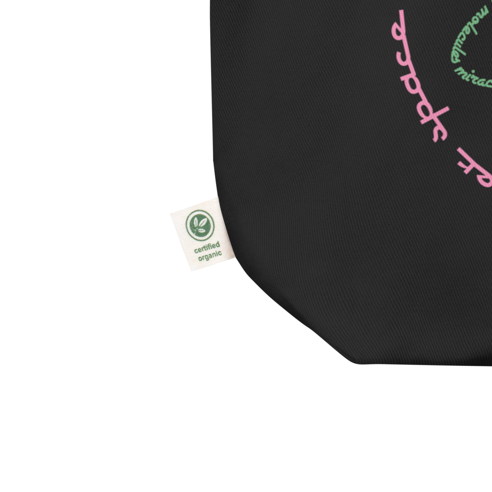 Logo inspired by the attraction with pink stylized retro text reading Adventures Thru Inner Space in a circle, surrounding atomic shaped text in green reading Miracles from Molecules, on a Black tote — fabric detail