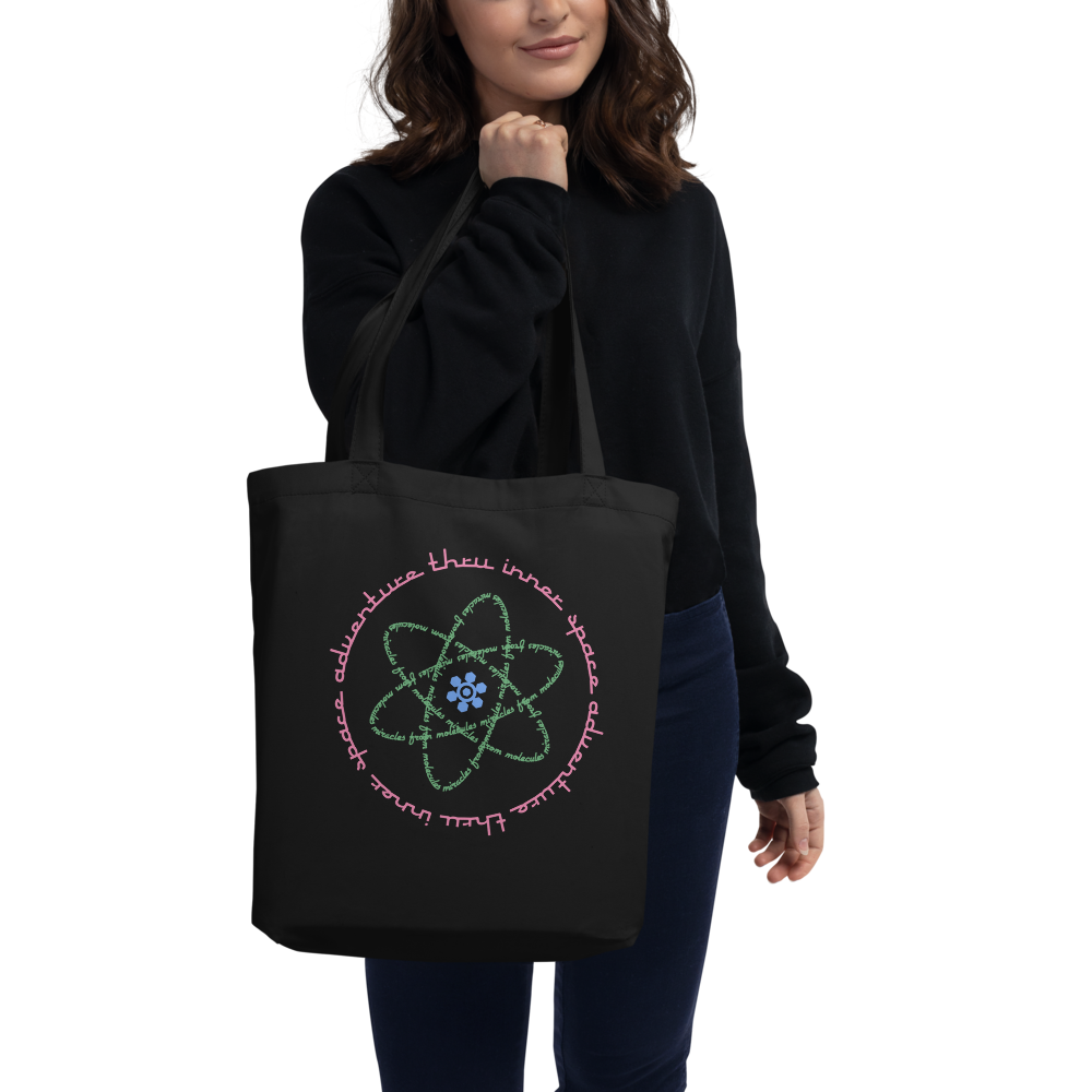 Logo inspired by the attraction with pink stylized retro text reading Adventures Thru Inner Space in a circle, surrounding atomic shaped text in green reading Miracles from Molecules, on a Black tote — worn stylishly by a model